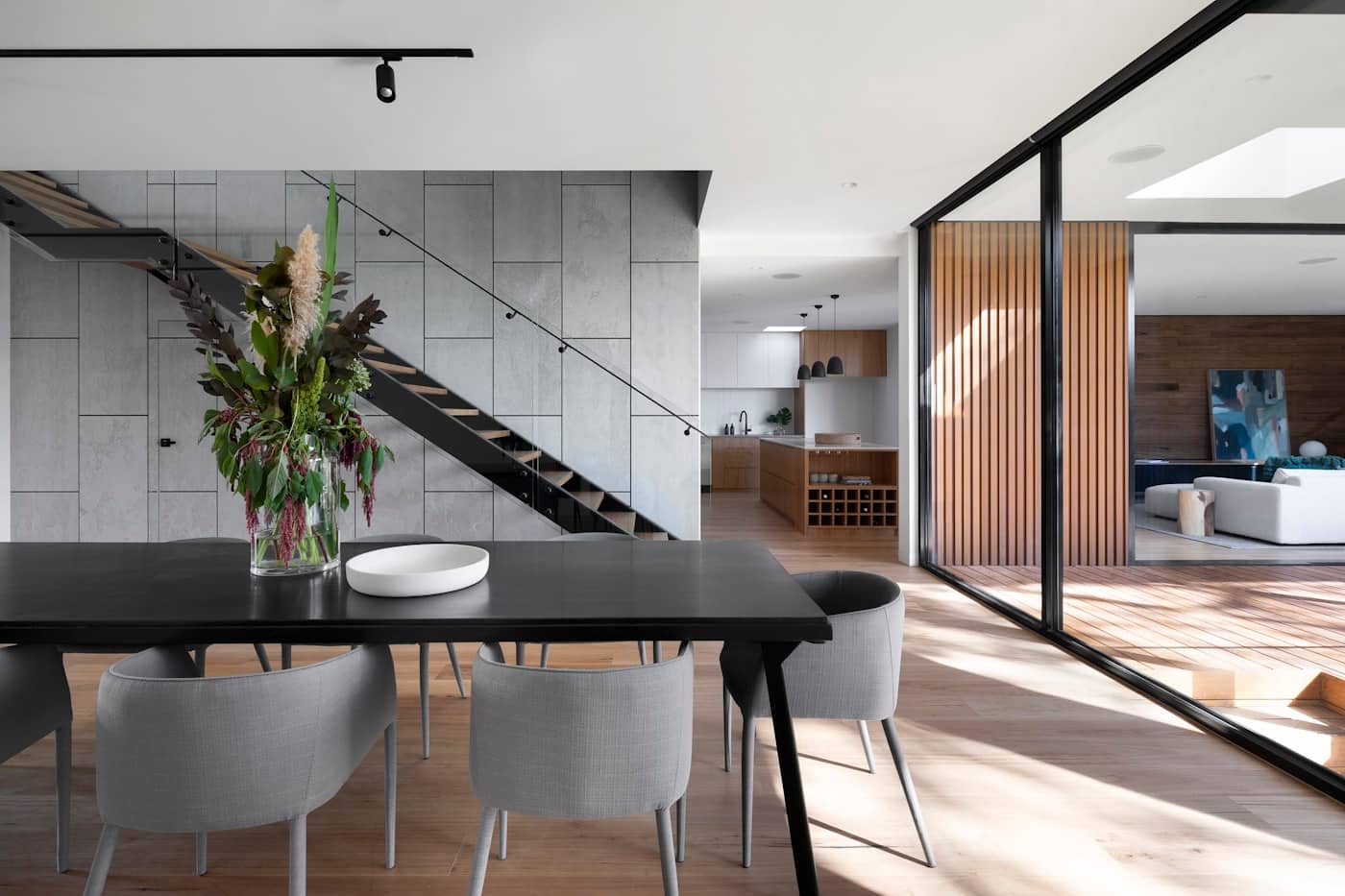 Open-plan dining room with timber stair and glass wall to the courtyard