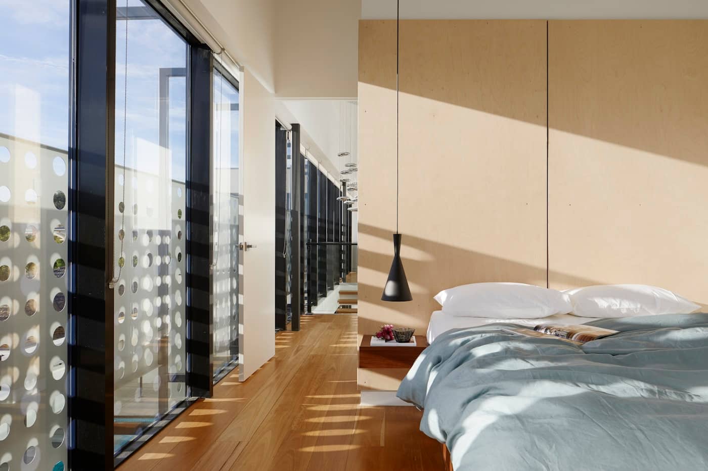 Bedroom suite addition with plywood feature wall and black-framed glazing