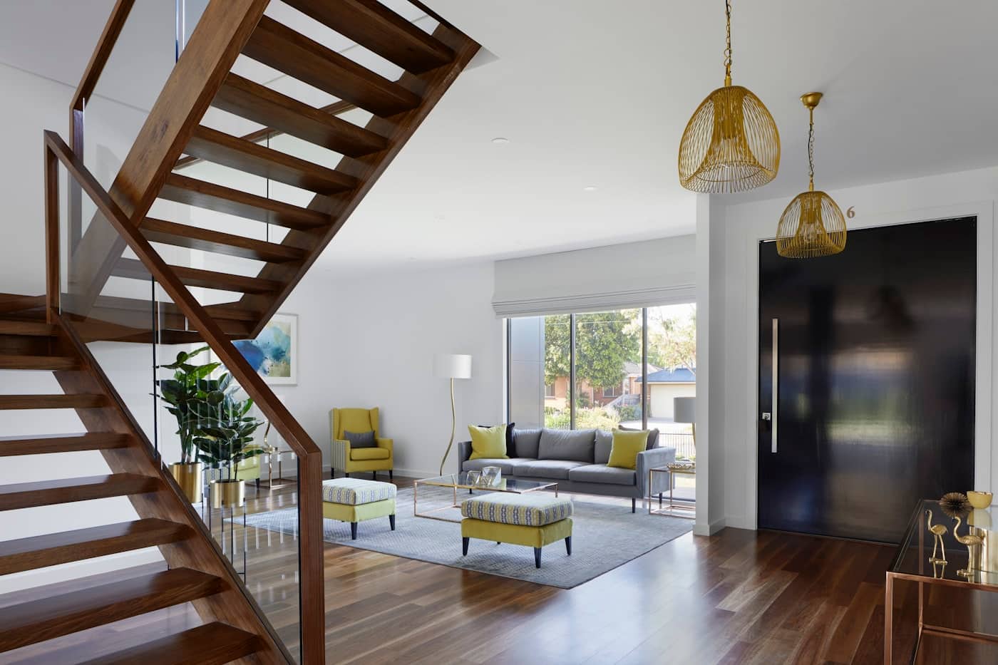 Entry hall with sculptural walnut staircase and black front door